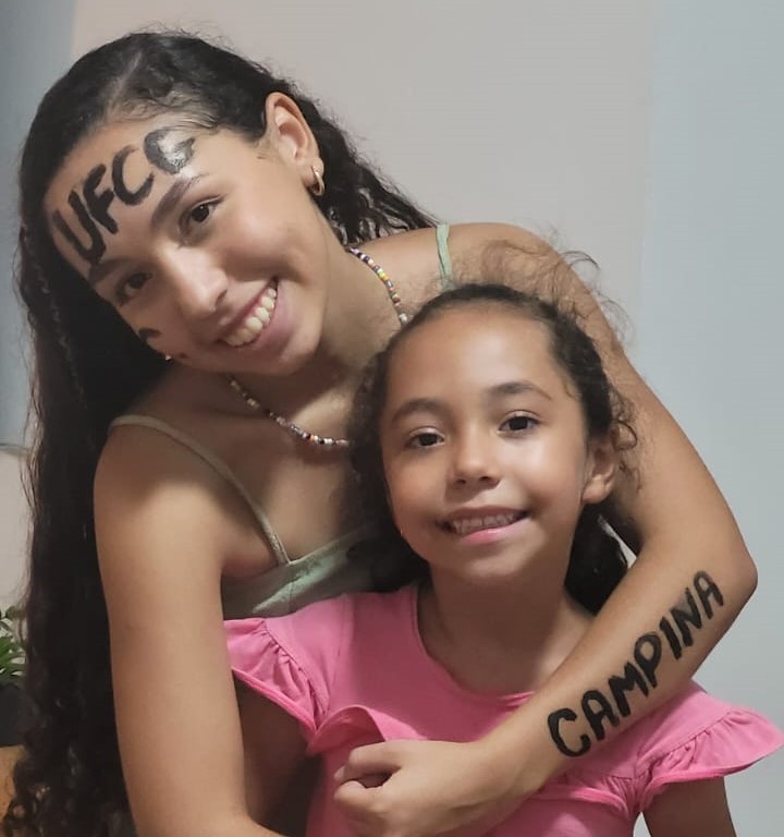 Adolescente abraçando irma mais nova, em comemoração a aprovação no vestibular