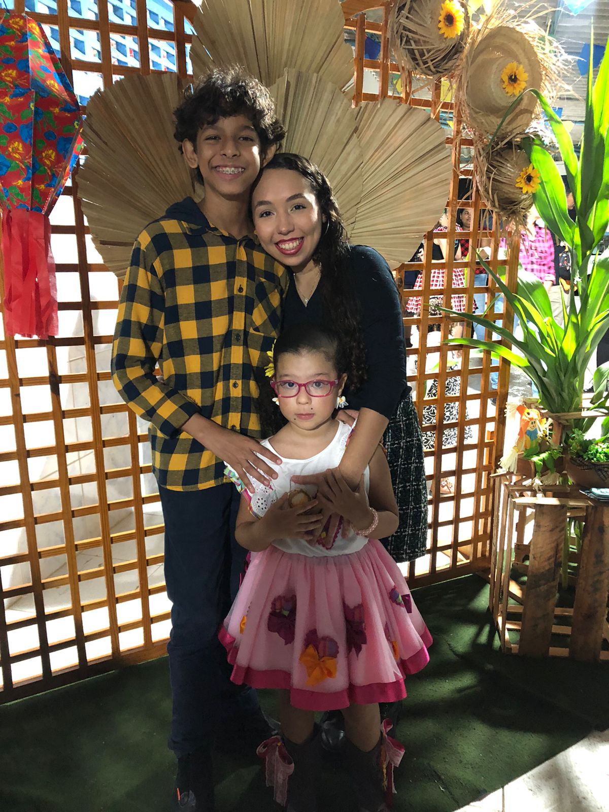 Um menino e duas meninas, todos com roupa de festa junina